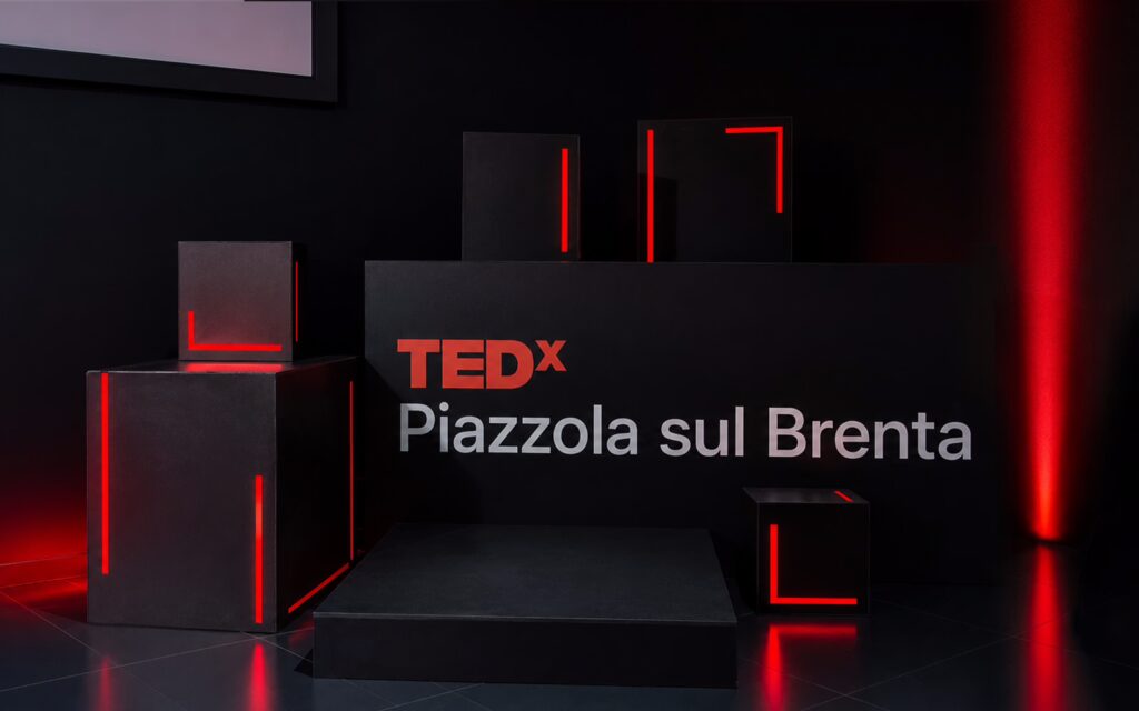 Allestimento scenografico TEDx con illuminazione rossa e installazione visiva contemporanea